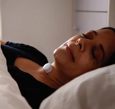 A woman asleep at home wearing the small Sámh neck sensor